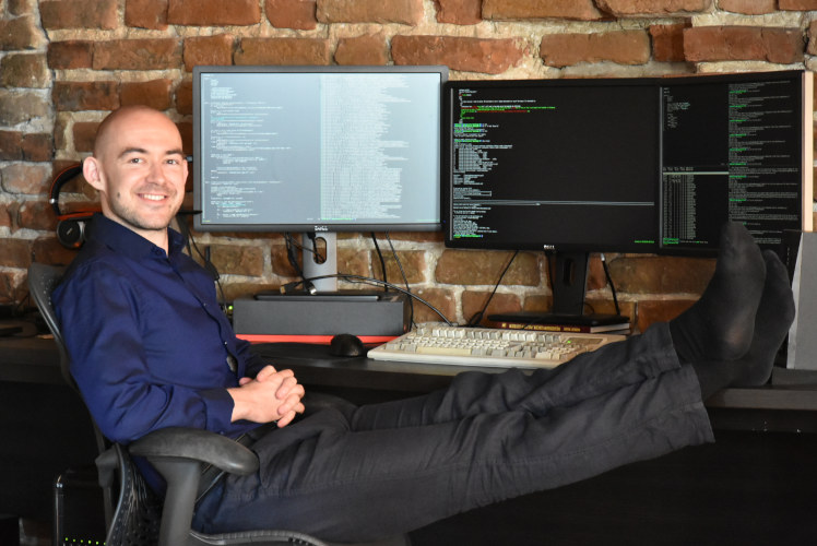 Michal working at a desk with monitors and a 1989 IBM Model M keyboard in 2019
