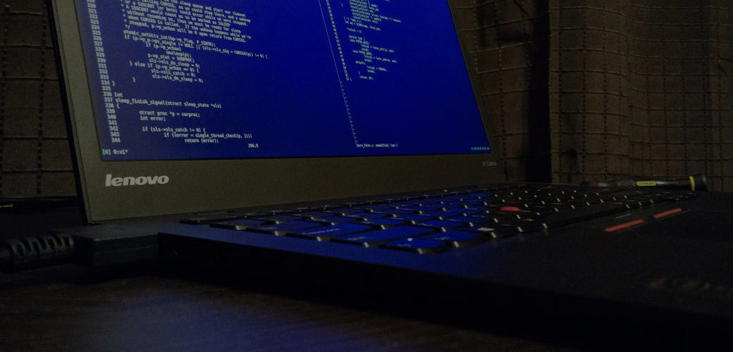 Laptop on a dark desk showing code on screen