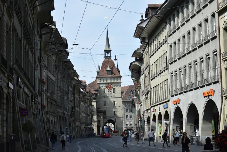 Orderly street in Bern with tram wires and a clock tower